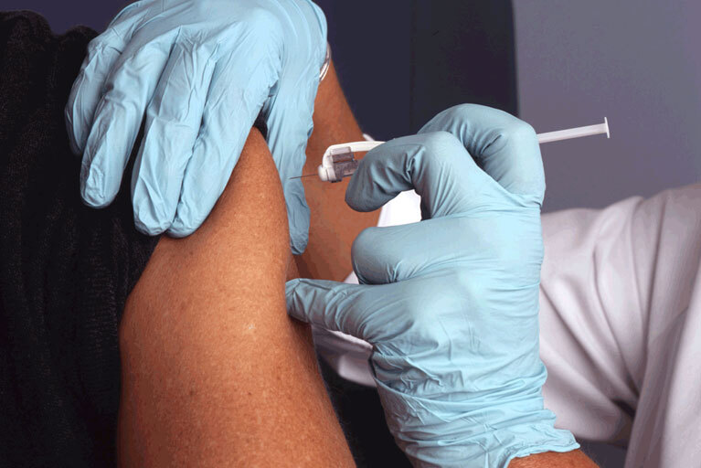 Warzenimpfung: In Oberarm wird Nadel injiziert - mit Handschuhen